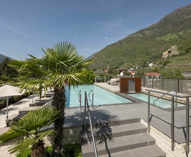 Poolterrasse mit Bergblick im Feldhof Eine Poolterrasse mit Liegen, Schirmen und Blick auf die Berge bei sonnigem Wetter.