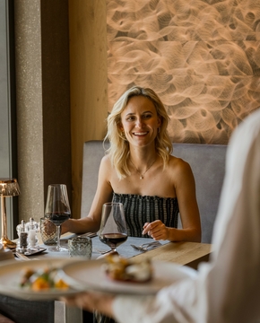 Ein Paar sitzt im Hotelrestaurant beim Abendessen, während ein Kellner den Tisch bedient.