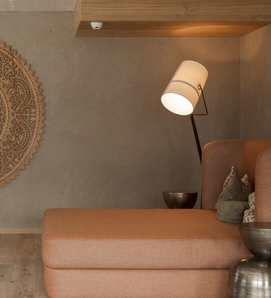 Eine gemütliche Ruheecke mit Sofa, Stehlampe und dekorativer Wandgestaltung in warmen Naturtönen.