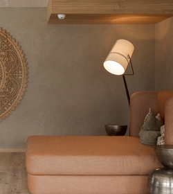 Eine gemütliche Ruheecke mit Sofa, Stehlampe und dekorativer Wandgestaltung in warmen Naturtönen.