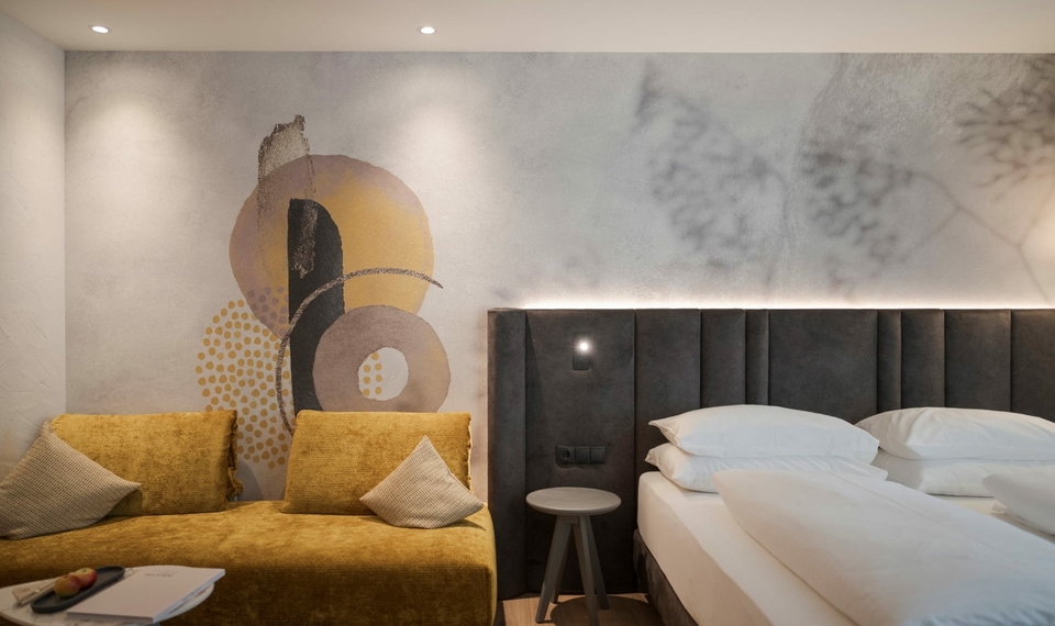 Doppelzimmer La Vita im Feldhof in Naturns Ein modernes Doppelzimmer mit gepolsterter Kuschelecke, Doppelbett und dekorativer Wandgestaltung.