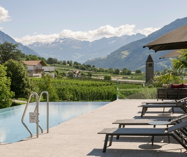 Ein Infinity-Pool mit Liegen und Blick auf die Berge in Naturns.