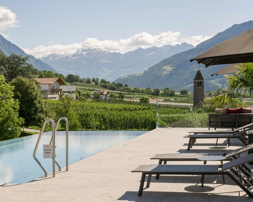 Ein Infinity-Pool mit Liegen und Blick auf die Berge in Naturns.