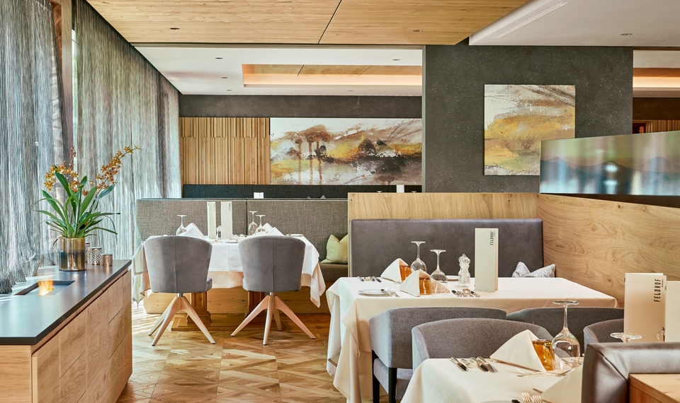 Ein stilvoll eingerichtetes Hotelrestaurant mit gedeckten Tischen, Holzdetails und Wandbildern.
