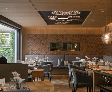 Restaurant im Feldhof DolceVita Resort Ein eleganter Restaurantbereich mit gedeckten Tischen, Bankett und warmem Holzinterieur.