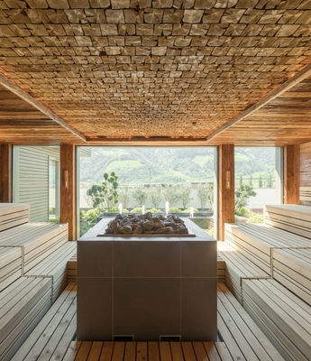 Sauna mit Panoramablick im Wellnesshotel Naturns Eine helle Panorama-Sauna mit Holzbänken und Blick auf die Berge.