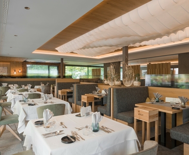 Hotelrestaurant im Feldhof DolceVita Resort Ein eleganter Speisesaal im Hotelrestaurant mit gedeckten Tischen und Sitznischen.