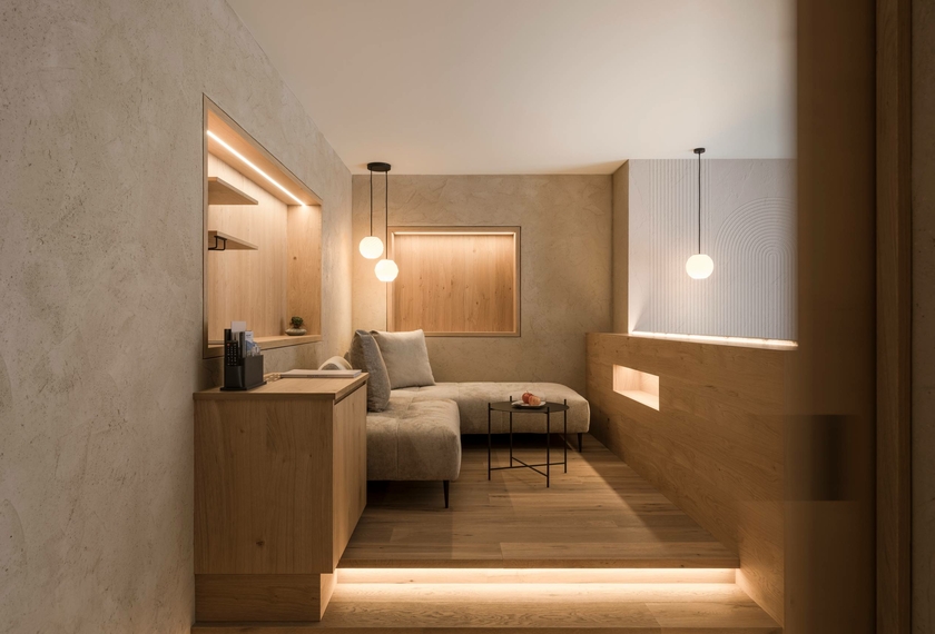 A modern suite with a sofa, wooden furnishings and soft ambient lighting at Feldhof in Naturns.