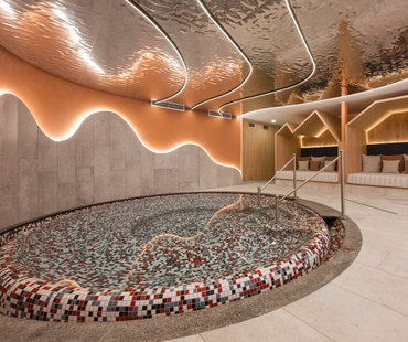 Ein Ruheraum im Spa mit rundem Mosaikbecken, Liegen und warm beleuchteter Holzverkleidung.