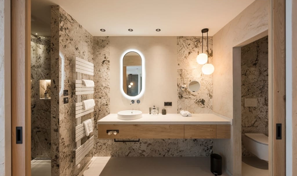 Ein modernes Bad mit Waschtisch, Spiegel und bodengleicher Dusche im Doppelzimmer Blumenwiese.
