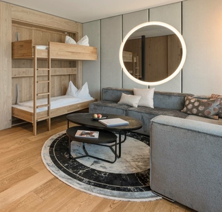 Ein modernes Familienzimmer mit Etagenbett, Sofa, rundem Spiegel und hellem Holzdesign.
