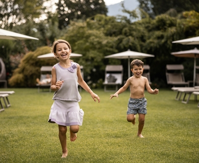 Familienurlaub im Garten des Feldhof Resorts Ein Mädchen und ein Junge laufen lachend über den Rasen im Garten des Feldhof DolceVita Resorts.