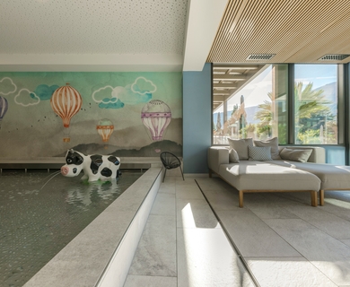 Ruheraum im Wellnesshotel Feldhof in Naturns Ein Ruheraum mit Liegen, großem Fenster und Wandmalerei mit Heißluftballons.