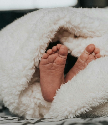 Babyfüße unter einer weichen Decke Kleine Babyfüße liegen eingewickelt in einer flauschigen Decke.