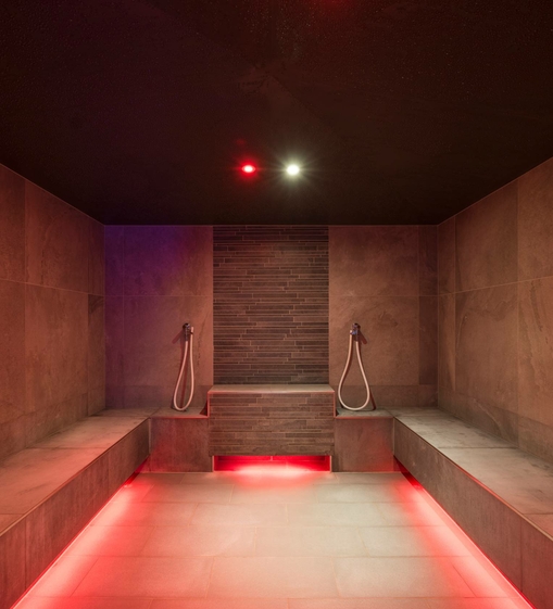 A modern sauna area with dark ceiling, stone walls and warm lighting at Feldhof.