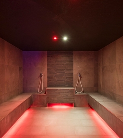 A modern sauna area with dark ceiling, stone walls and warm lighting at Feldhof.