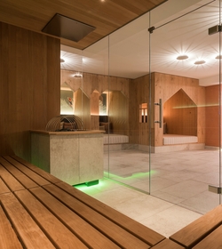 Eine Holzsauna mit Blick in den hellen Wellnessbereich des Family Spa im Feldhof.
