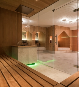 Eine Holzsauna mit Blick in den hellen Wellnessbereich des Family Spa im Feldhof.