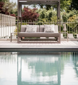 Un lettino lounge con baldacchino si trova a bordo piscina davanti a un giardino.