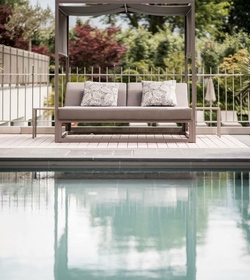 Un lettino lounge con baldacchino si trova a bordo piscina davanti a un giardino.