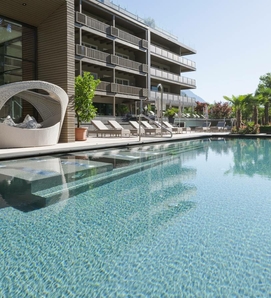 Una grande piscina all'aperto con lettini davanti al moderno edificio dell'hotel.