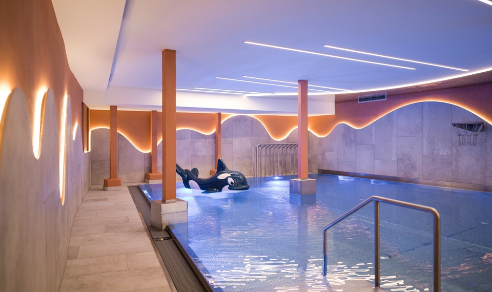 Ein Innenpool im Family Spa mit sanfter Beleuchtung und Liegebereich nebenan.