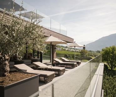 Liegen und Sonnenschirme auf der Terrasse des Sky Spa mit Blick auf die Berge.