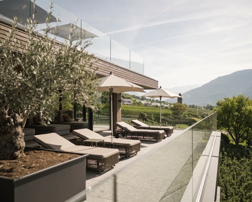 Liegen und Sonnenschirme auf der Terrasse des Sky Spa mit Blick auf die Berge.