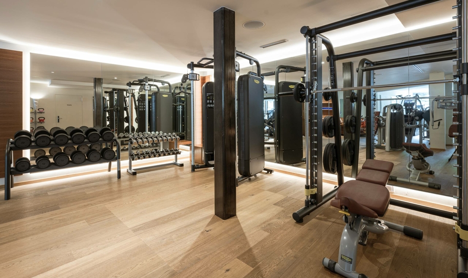 Ein moderner Fitnessraum mit Kraftgeräten, Hanteln und Spiegelwänden im Feldhof.