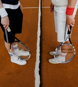 Two tennis players stand with rackets at the net on an indoor court.