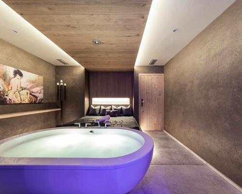 A private spa room with a whirlpool, loungers and soft ambient lighting.