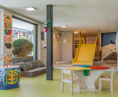Spielzimmer im Feldhof DolceVita Resort Ein heller Spielraum mit Rutsche, Tisch und Bastelmaterial im Feldhof DolceVita Resort.