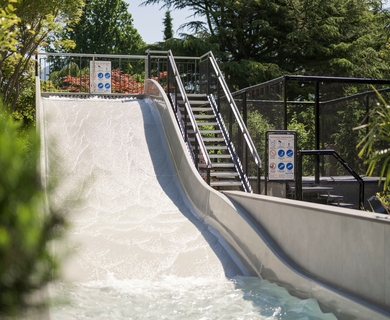 Wasserrutsche im Hotelgarten des Feldhof Eine breite Wasserrutsche führt in einen Poolbereich im grünen Hotelgarten.