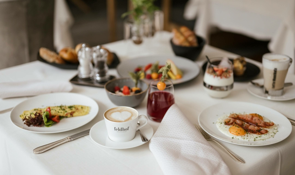 Ein gedeckter Frühstückstisch mit Kaffee, Eierspeise, Obst und Broten im Hotelrestaurant.