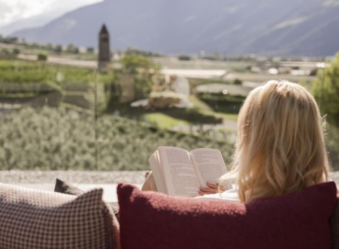 Terrazza per la lettura con vista montagne Una donna legge su una terrazza con il paesaggio e le montagne sullo sfondo.