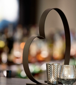Eine Herzdeko steht auf der Bar vor unscharfen Gläsern und warmem Licht.