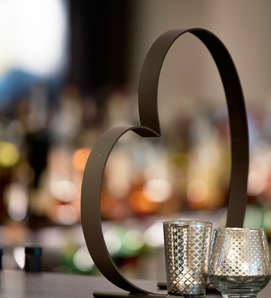 Eine Herzdeko steht auf der Bar vor unscharfen Gläsern und warmem Licht.