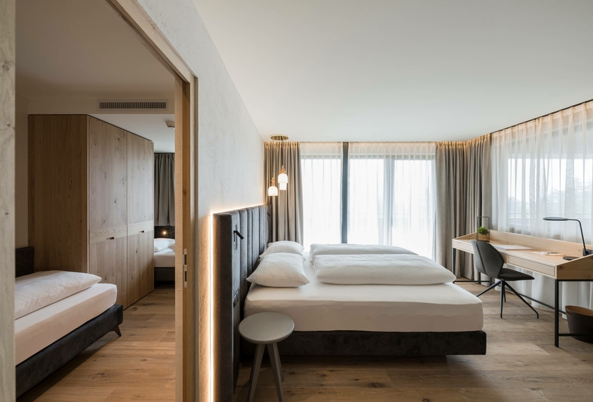 Suite con whirlpool al Feldhof di Naturno Una suite luminosa con letto, zona salotto e scrivania, collegata a una stanza adiacente con divano letto.