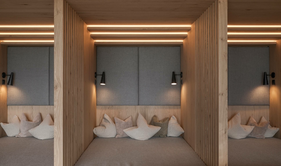 Tre accoglienti nicchie relax con cuscini e finiture in legno caldo in un’area wellness.