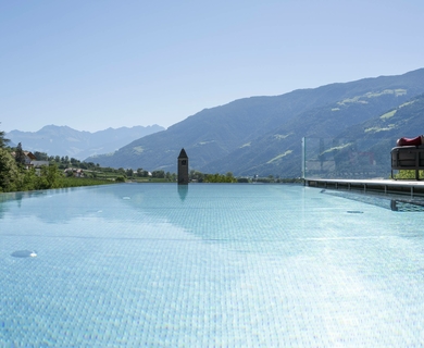 Infinity Pool im Feldhof mit Bergblick Der Infinity-Pool des Feldhof DolceVita Resort liegt vor einer Bergkulisse und weitläufiger Landschaft.