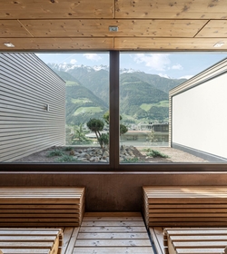 Two wooden benches in a sauna with a large window and mountain views outside.