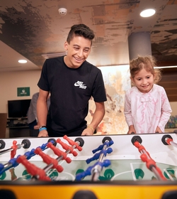 Ein Junge und ein Mädchen spielen gemeinsam Tischfußball im Innenbereich.
