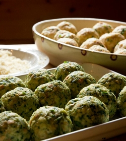Auf einer Servierplatte liegen Spinatknödel neben einem Teller mit Käse im Hotelrestaurant.