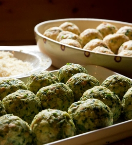 Auf einer Servierplatte liegen Spinatknödel neben einem Teller mit Käse im Hotelrestaurant.