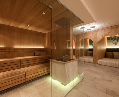 Sauna im Wellnesshotel in Naturns Ein holzverkleideter Saunabereich mit Glasofenkamin und Ruheliegen im Wellnesshotel.