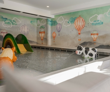 Ein Innenpool im Family Spa mit Spieltieren und bunter Wandmalerei mit Heißluftballons.