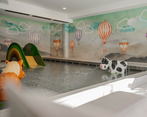 Ein Innenpool im Family Spa mit Spieltieren und bunter Wandmalerei mit Heißluftballons.