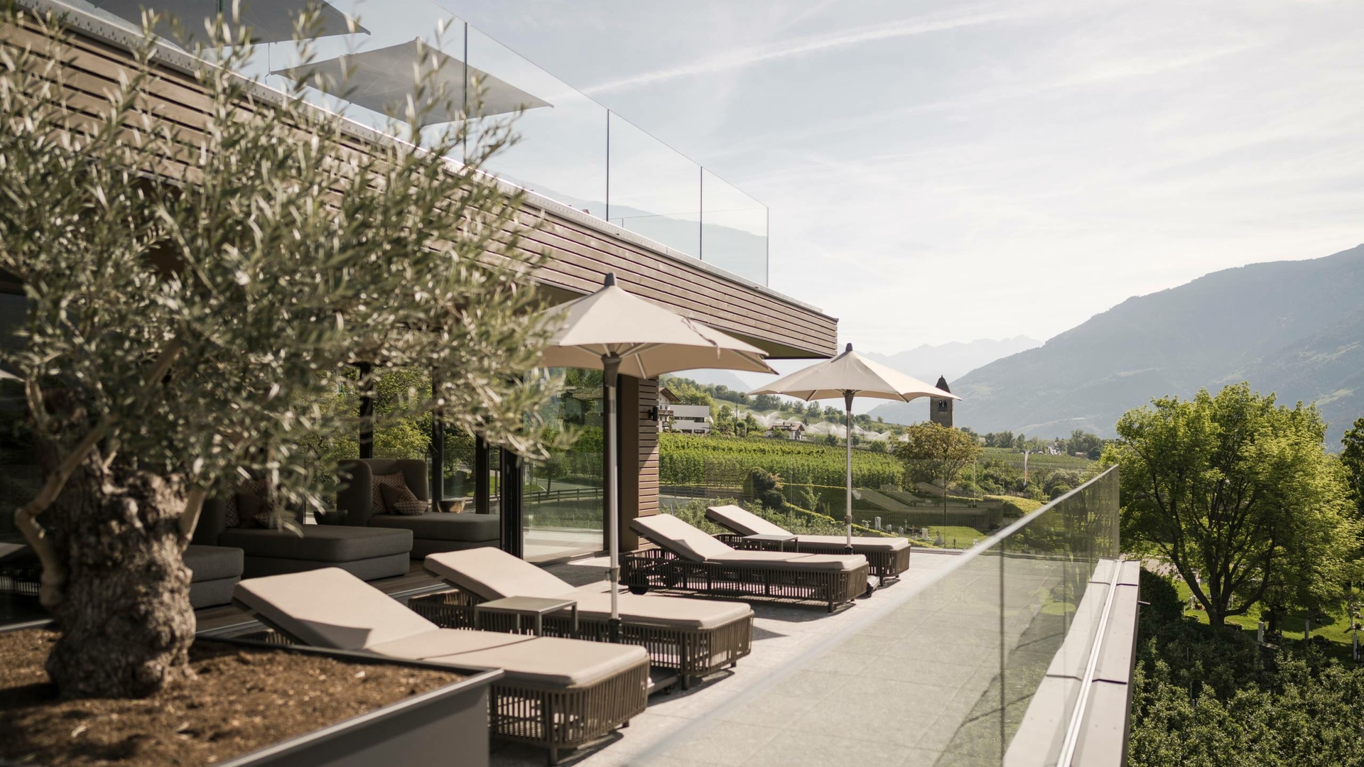 Liegen und Sonnenschirme auf der Panoramaterrasse mit Blick auf die Berge im Sky Spa.