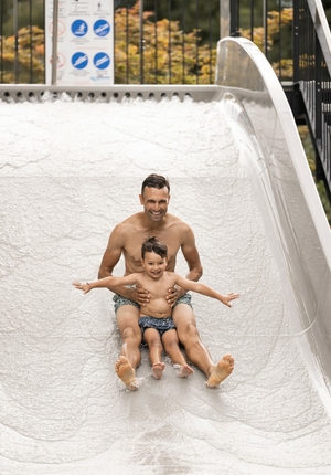 A man and a child slide down a white water slide together.