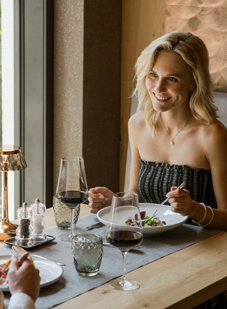 Una coppia siede nel ristorante dell’hotel e gusta una cena elegante al tavolo vicino alla finestra.